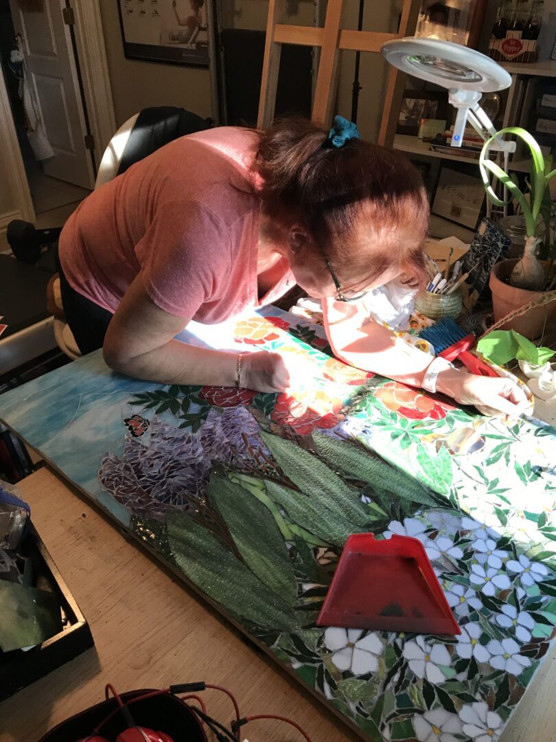 A woman is working on a mosaic picture.